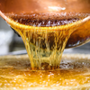Our supplier Confiserie des Hautes Vosges pouring preparation of candies from copper cauldron at their workplace.