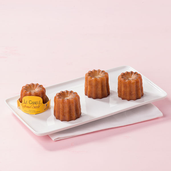 Four large canelés de Bordeaux on a plate. Made in Bordeaux, France
