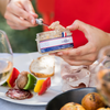 Someone getting some pâté out of a opened jar to spread on bread.