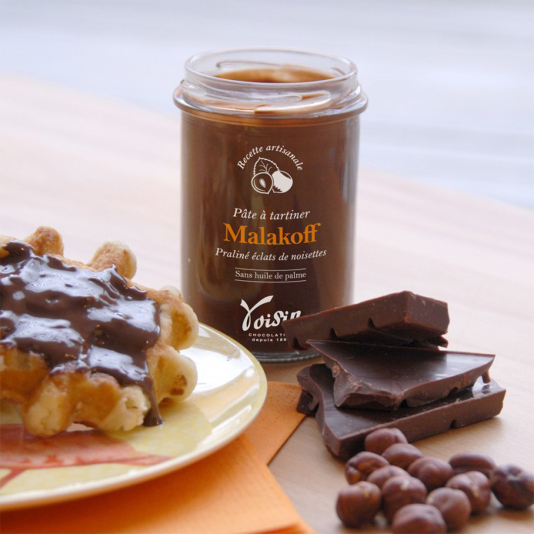 Jar of Voisin's milk chocolate malakoff spread opened with some spread on a raffle.