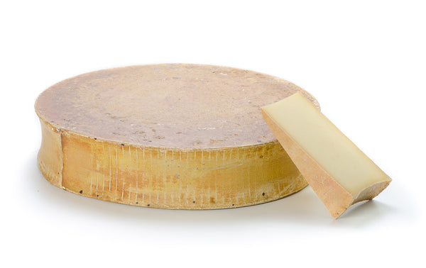The whole Beaufort cheese with one slice on the side.
