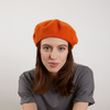 Model wearing Laulhère's 100% French merino wool Veritable beret - tangerine