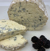 Fourme d'Ambert cheese in the background with two slices and blackberries in the foreground