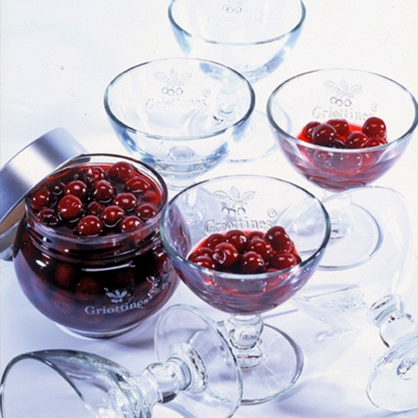 Coupes glasses for griottines Peureux, with some griottines in some of them and a jar of griottines opened