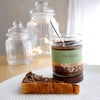 Jar of Angelina's gianduja spread open with some spread on a slice of bread in the foreground