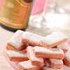 Pink biscuits on a plate, bottle of champagne in the background