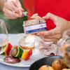 Someone getting some pâté out of a opened jar to spread on bread. 