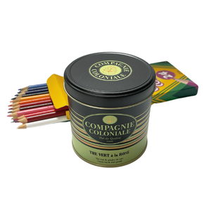 Tin of Compagnie Coloniale green tea with roses and petal of roses loose leaves with a box of crayons in the background