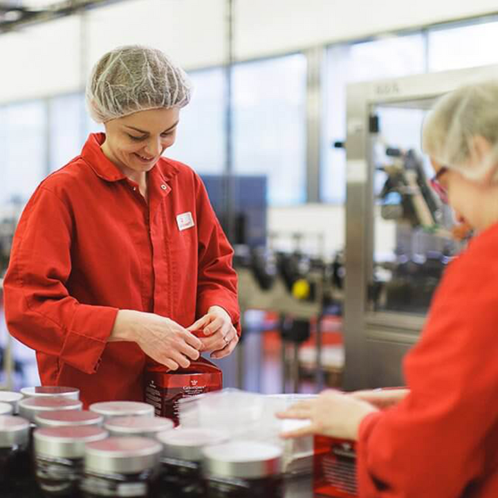 Staff busy packing jars of griottines at Distilleries Peureux workplace.