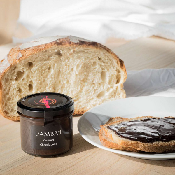 Jar of L'Ambr'1's caramel spread with some spread on a slice of bread