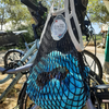 Black ecru Filt 1860's 100% cotton net shopping bag, hung at the handle of a bike, with towel and sunglasses inside