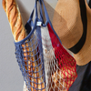 Blue-white-red Filt 1860's 100% cotton net shopping bag hung near a hat, with baguette and bread inside