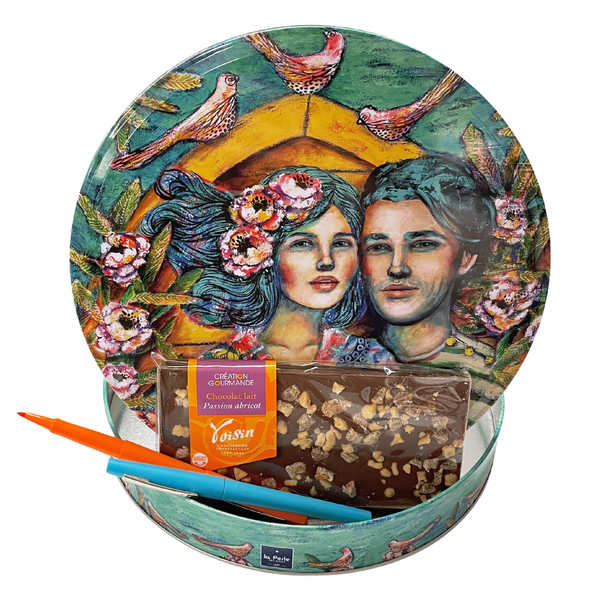 'Love in Tahiti' collector tin open with Voisin's milk chocolate gourmande bar with passion fruit and apricot and 2 pens