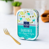 Tin of sardines with organic seeweed and capers, with a fork in the foreground