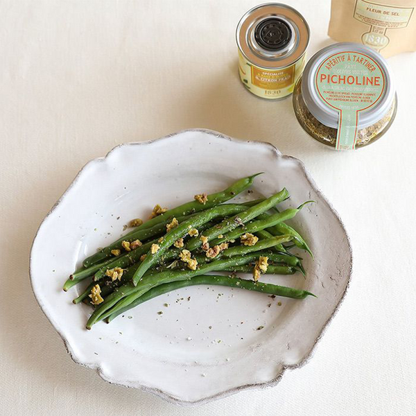 Jar of Maison Bremond 1830's Picholine olive spread with a plate of French beans in the foreground.